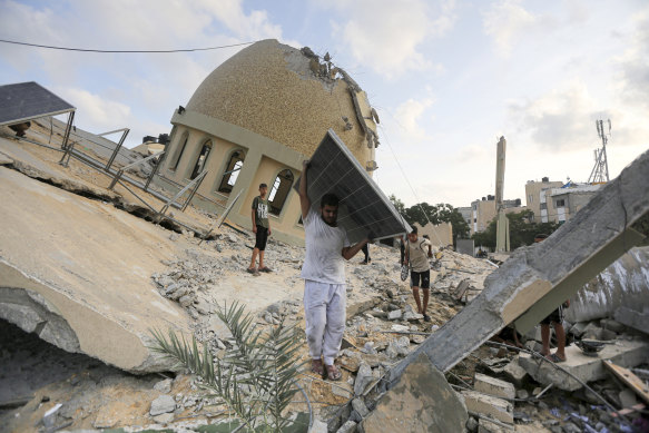 A man takes a solar panel from a mosque destroyed in an Israeli air strike in Khan Younis, Gaza Strip.